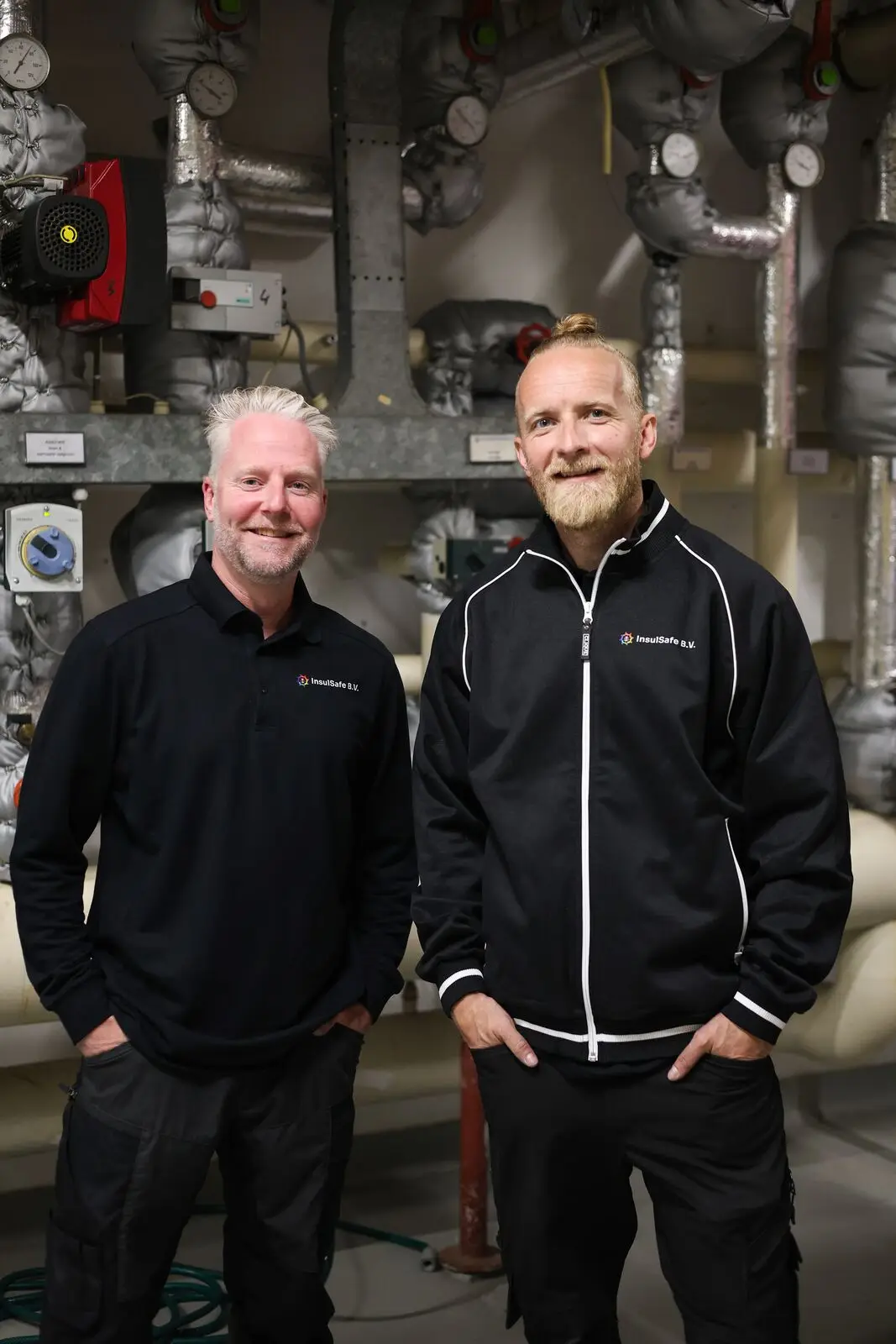 Twee InsulSafe-monteurs aan het werk in een technische ruimte